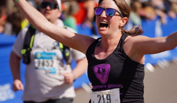 Happy female marathoner crossing the finish line