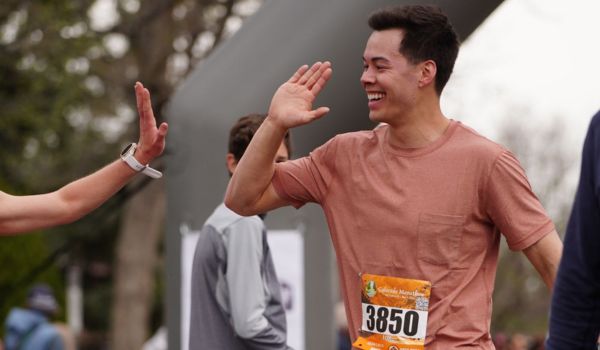 Male 10k finisher giving high-fives at the finish line
