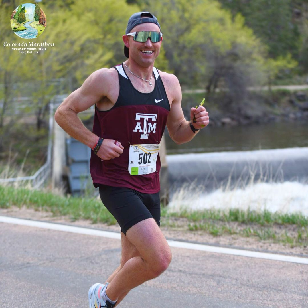 Male Colorado Marathon participant smiling as he runs down the Poudre Canyon