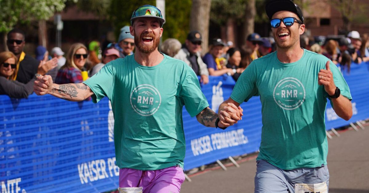 Two excited runners crossing the finish line together for marathon success