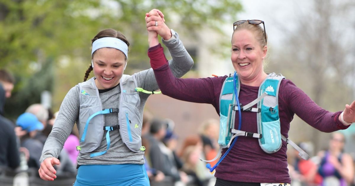 Two runners crossing the finish line at the Colorado Marathon, finishing strong with no altitude sickness